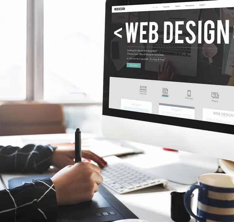 Una persona en un escritorio con una pantalla de computadora mostrando un diseño web para agencia SEO.